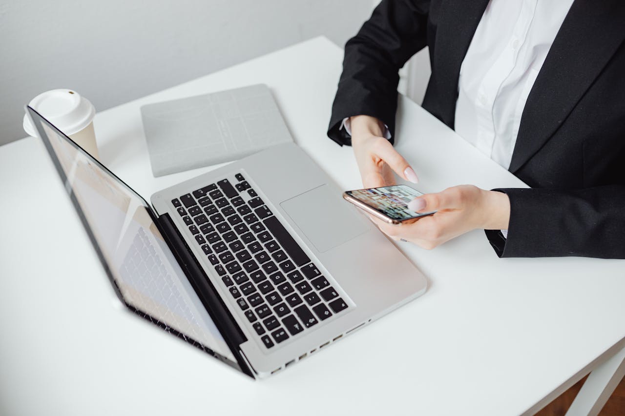 Home Businesswoman using smartphone at desk with laptop and coffee cup.